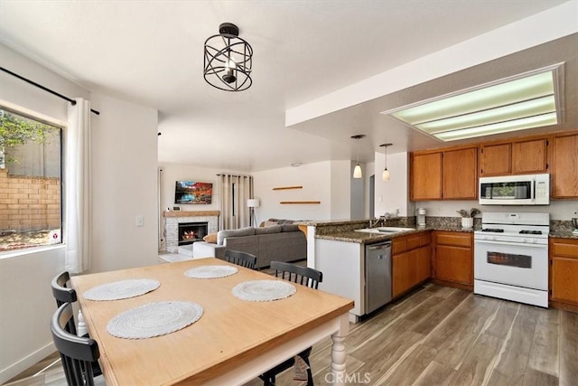 6517 Via Del Prado, Chino Hills, CA 91709 - kitchen with white appliances, brown cabinets, light wood-style floors, a warm lit fireplace, and a peninsula