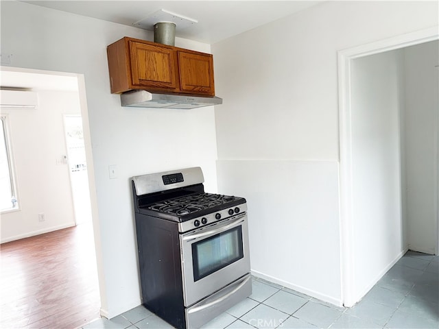 1330 S Reservoir St, Pomona, CA 91766 - kitchen featuring stainless steel gas range, under cabinet range hood, a wall unit AC, brown cabinets, and baseboards