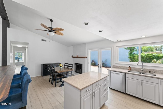 1805 Adelaide Ct, Oxnard, CA 93035 - kitchen with stainless steel dishwasher, a sink, a brick fireplace, vaulted ceiling, and light wood finished floors