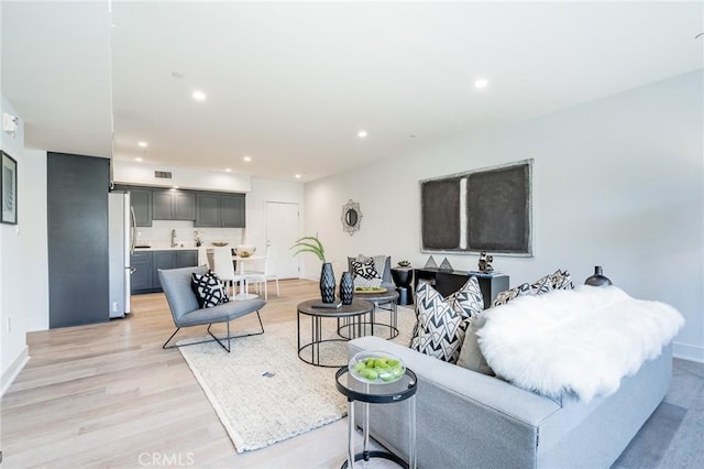 living room featuring light wood-style flooring, recessed lighting, and baseboards
