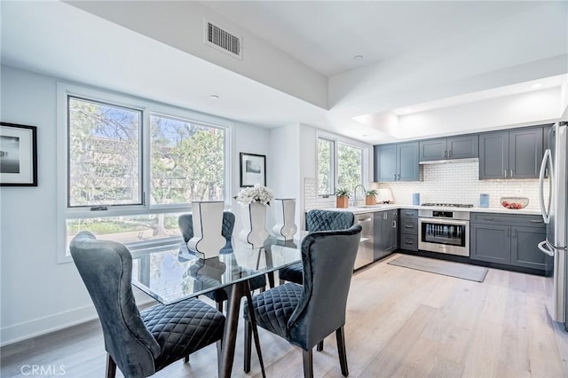 dining space with light wood-type flooring, baseboards, and a tray ceiling