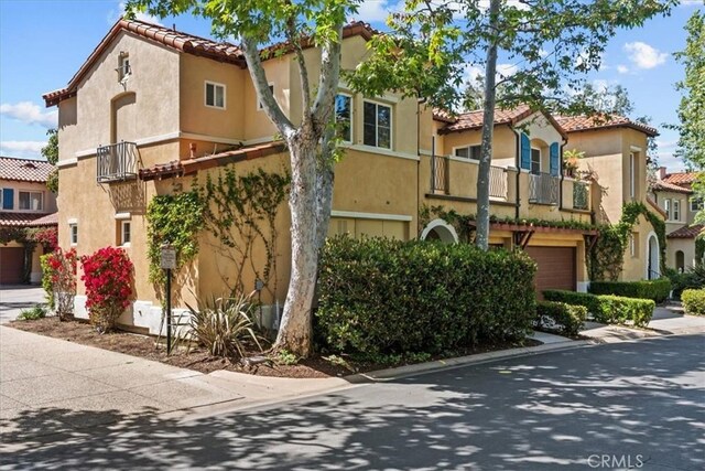 1 Firenze Ct, Newport Coast, CA 92657 - view of front of home with a balcony, a garage, a tiled roof, and stucco siding