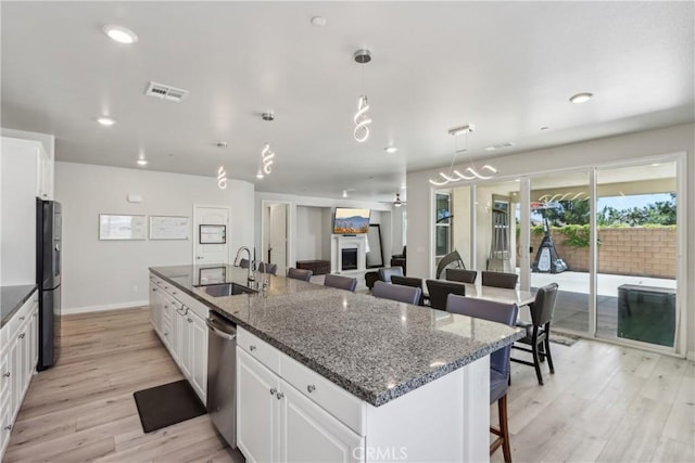 29167 Moraga St, Menifee, CA 92584 - kitchen with a sink, freestanding refrigerator, stainless steel dishwasher, light wood-style floors, and a kitchen breakfast bar