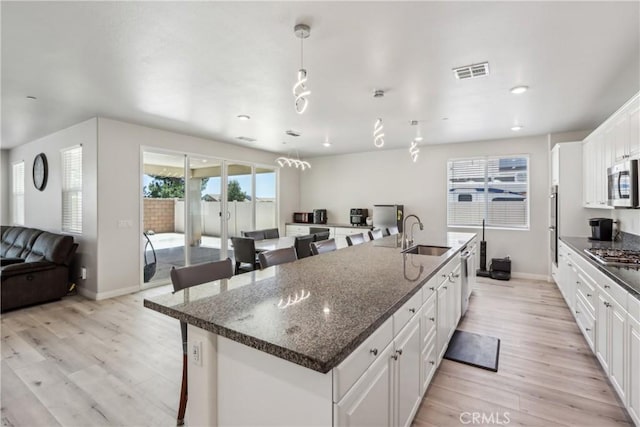 29167 Moraga St, Menifee, CA 92584 - kitchen featuring a sink, stainless steel microwave, a kitchen breakfast bar, light wood-style floors, and recessed lighting