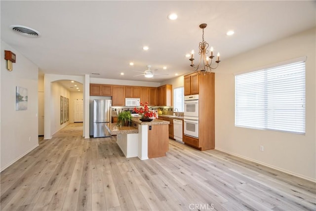 28046 Crystal Spring Dr, Menifee, CA 92584 - kitchen featuring white appliances, arched walkways, a ceiling fan, light wood-style floors, and a kitchen island
