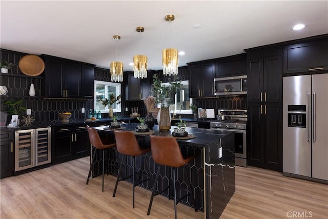 4325 N Country Club Ln, Long Beach, CA 90807 - kitchen featuring appliances with stainless steel finishes, beverage cooler, dark countertops, dark cabinetry, and recessed lighting