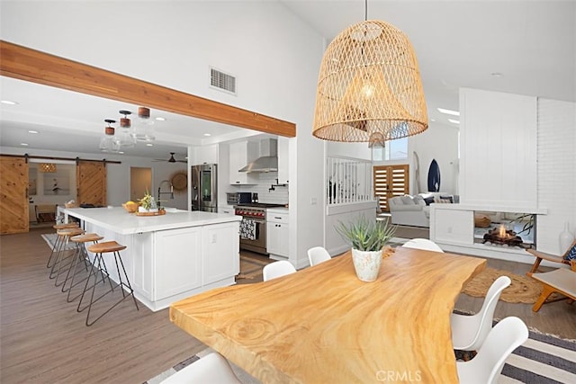 24132 Snipe Ln, Laguna Niguel, CA 92677 - dining room with a chandelier, a barn door, light wood-style flooring, recessed lighting, and a high ceiling
