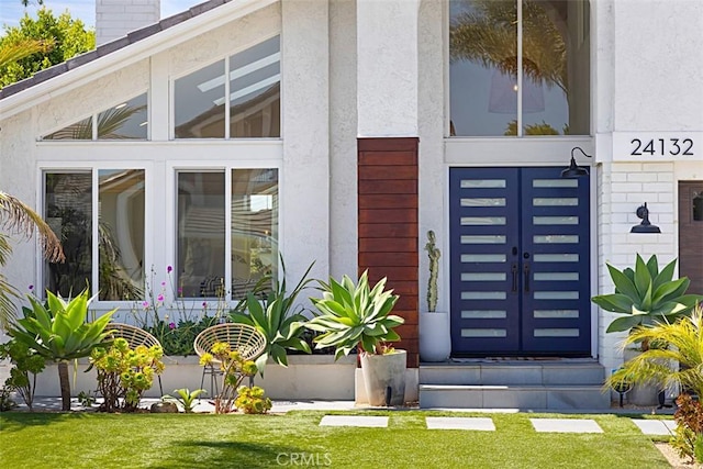 24132 Snipe Ln, Laguna Niguel, CA 92677 - view of exterior entry featuring a lawn, stucco siding, and a chimney