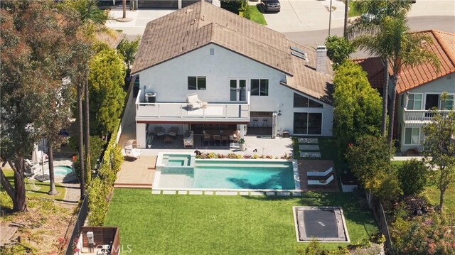 24132 Snipe Ln, Laguna Niguel, CA 92677 - rear view of house featuring stucco siding, a pool with connected hot tub, a lawn, a patio area, and a balcony
