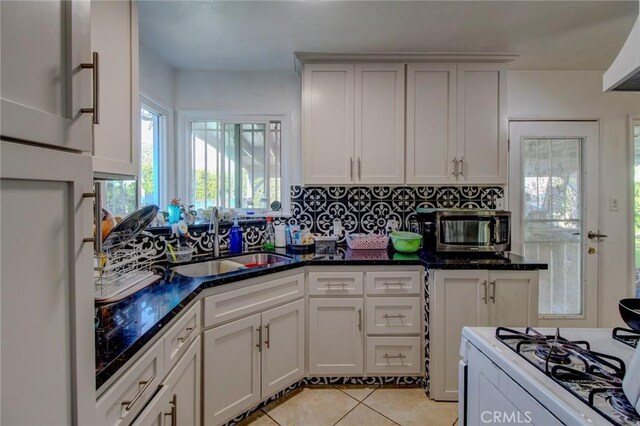 1419 S Hesperian St, Santa Ana, CA 92704 - kitchen with a sink, stainless steel microwave, white range with gas stovetop, decorative backsplash, and light tile patterned flooring