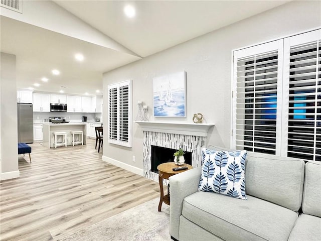 24082 Calendula, Mission Viejo, CA 92692 - living room with recessed lighting, light wood finished floors, vaulted ceiling, a fireplace, and baseboards