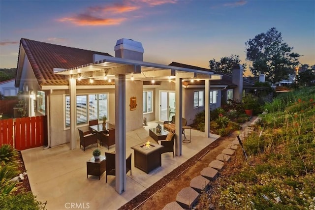 24082 Calendula, Mission Viejo, CA 92692 - back of property at dusk with an outdoor fire pit, a pergola, a chimney, a patio, and stucco siding