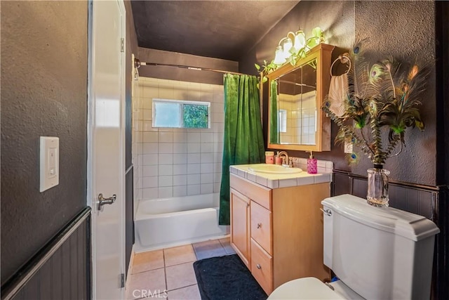 bathroom with tile patterned flooring, toilet, shower / tub combo, vanity, and a textured wall