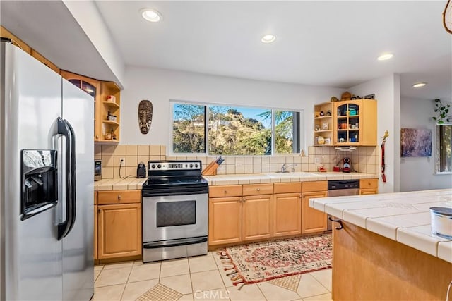 kitchen with appliances with stainless steel finishes, open shelves, a sink, tile countertops, and recessed lighting