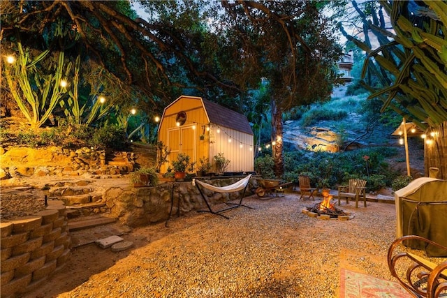 view of yard featuring a fire pit, a shed, and an outdoor structure