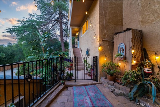 exterior entry at dusk featuring stucco siding and a balcony