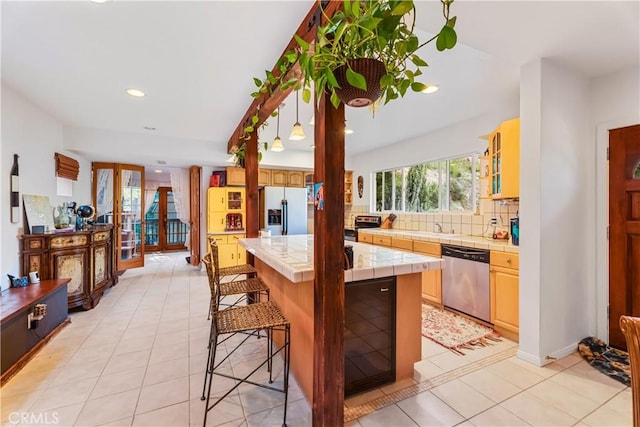 kitchen with appliances with stainless steel finishes, tile counters, a breakfast bar area, a kitchen island, and tasteful backsplash