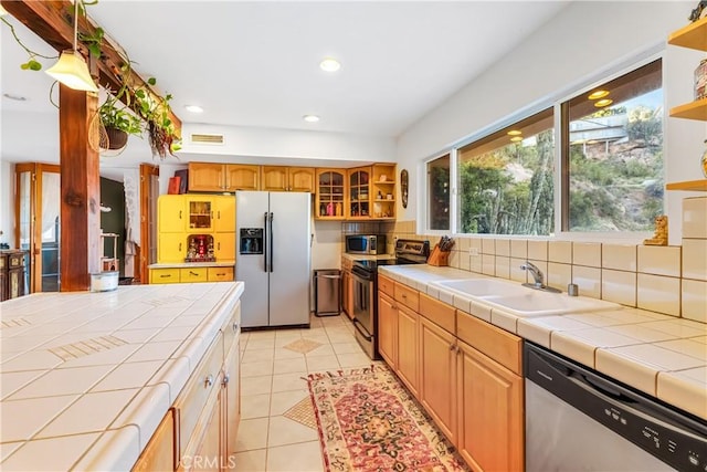 kitchen featuring stainless steel appliances, open shelves, tile countertops, and recessed lighting