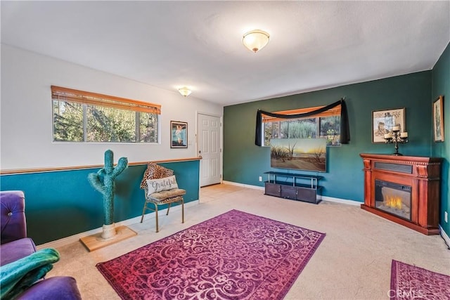 living area with carpet flooring, a glass covered fireplace, and baseboards