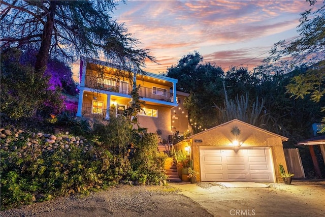 view of front of property with a balcony, driveway, stairway, stucco siding, and a garage