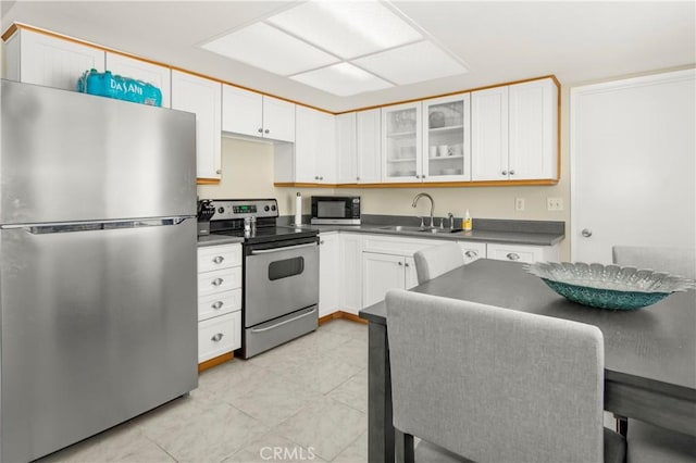 9653 Spyglass Ave Unit 99, Desert Hot Springs, CA 92240 - kitchen featuring stainless steel appliances, a sink, dark countertops, glass insert cabinets, and white cabinetry