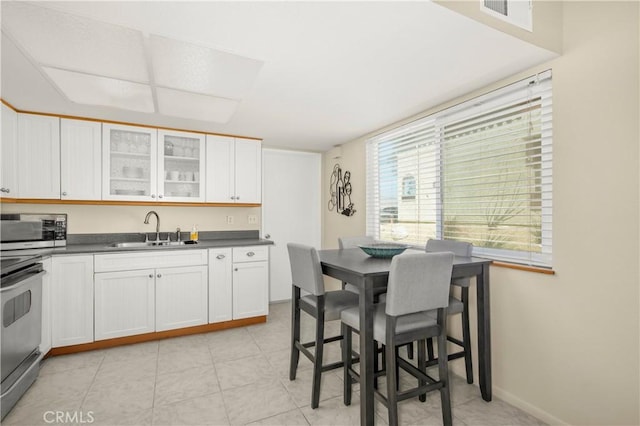 9653 Spyglass Ave Unit 99, Desert Hot Springs, CA 92240 - kitchen with a sink, stainless steel appliances, dark countertops, glass insert cabinets, and white cabinetry
