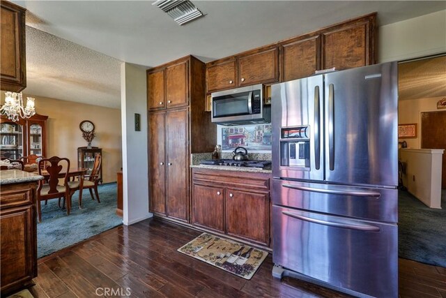 22972 Valley View Dr, Crestline, CA 92325 - kitchen with appliances with stainless steel finishes, dark wood-style flooring, a chandelier, light stone countertops, and a textured ceiling