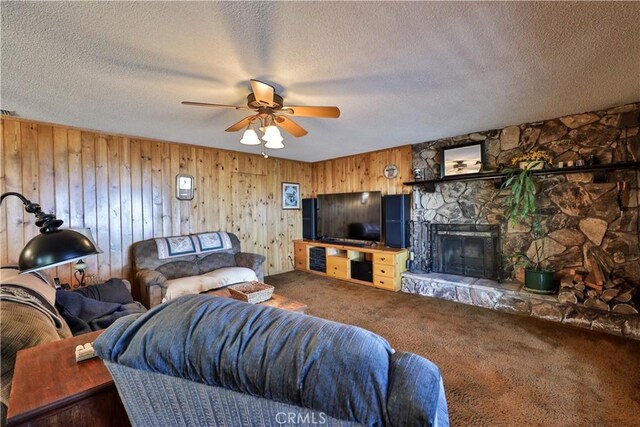 22972 Valley View Dr, Crestline, CA 92325 - carpeted living room with ceiling fan, a textured ceiling, a stone fireplace, and wooden walls