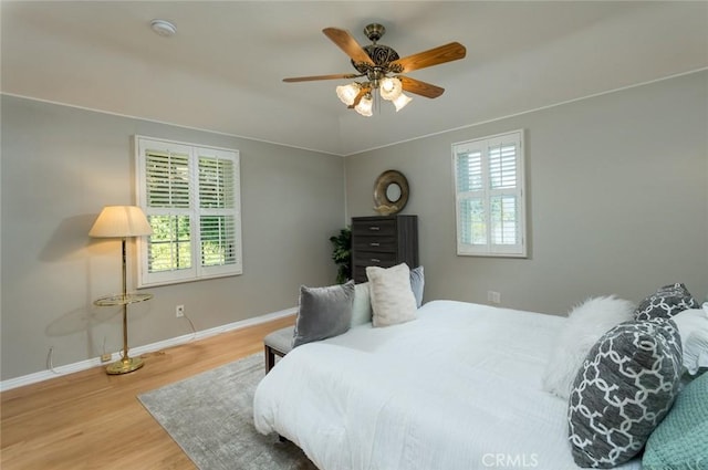 bedroom with wood finished floors, baseboards, and ceiling fan