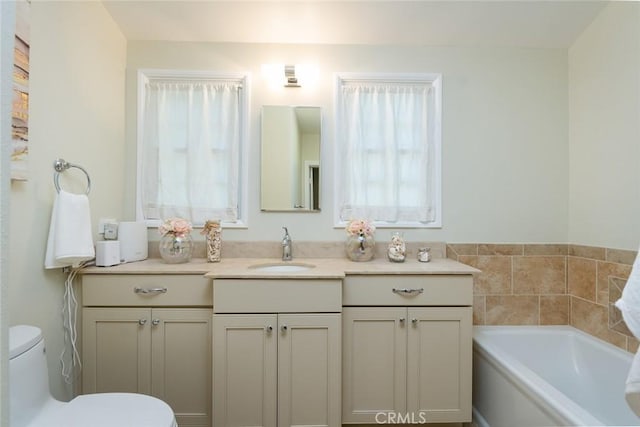 bathroom with toilet, vanity, and a bath