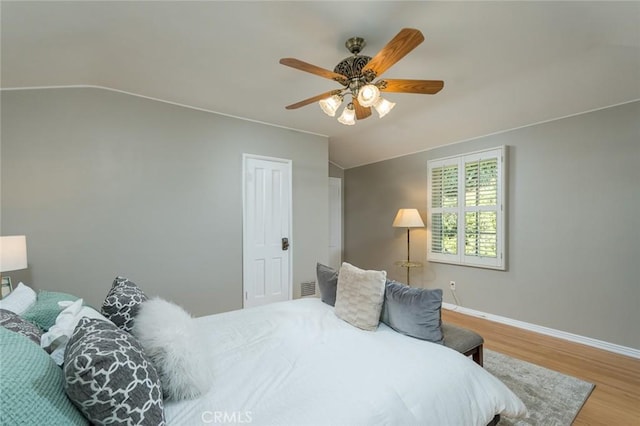 bedroom with lofted ceiling, wood finished floors, baseboards, and a ceiling fan