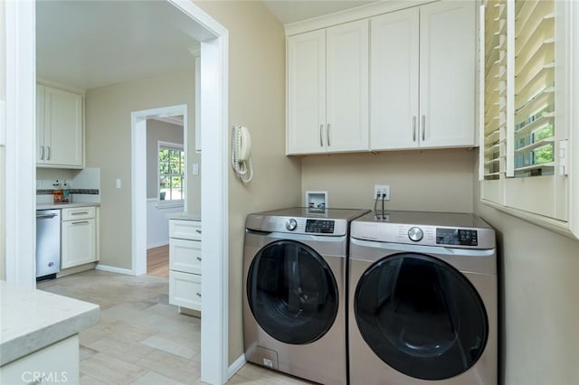 clothes washing area featuring washer and dryer, cabinet space, and baseboards