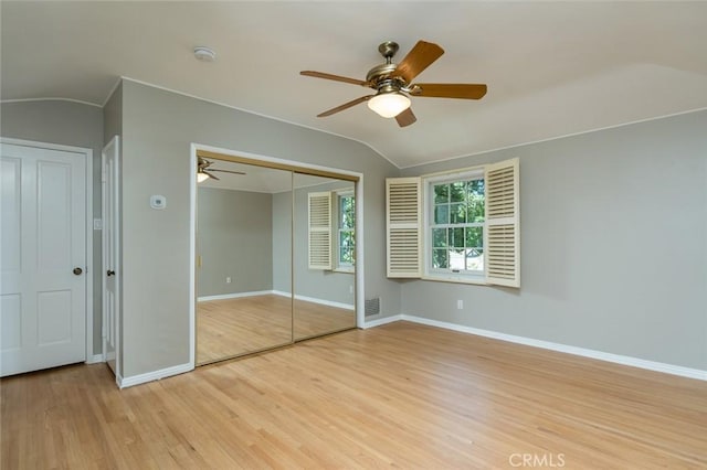 unfurnished bedroom with lofted ceiling, light wood-style flooring, baseboards, a closet, and a ceiling fan