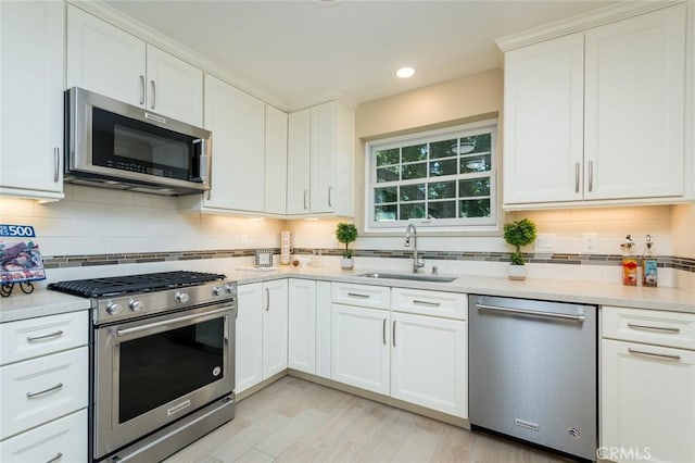 kitchen featuring appliances with stainless steel finishes, a sink, backsplash, light countertops, and recessed lighting