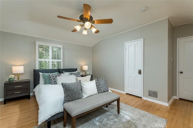 bedroom featuring light wood finished floors, baseboards, lofted ceiling, and ceiling fan