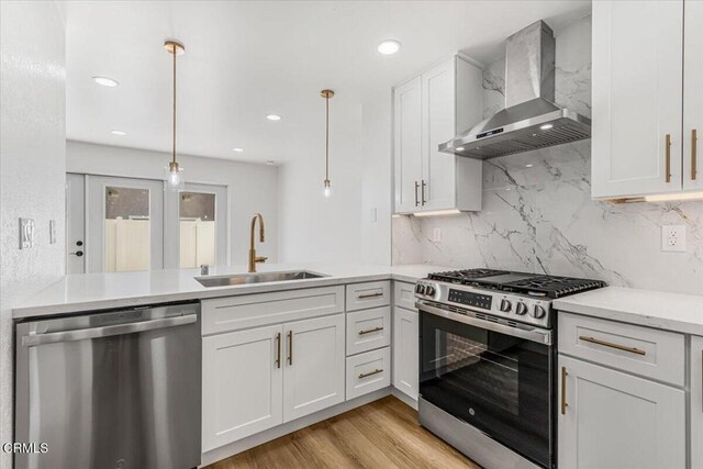 1314 Gina Dr, Oxnard, CA 93030 - kitchen featuring wall chimney range hood, appliances with stainless steel finishes, tasteful backsplash, a peninsula, and white cabinetry