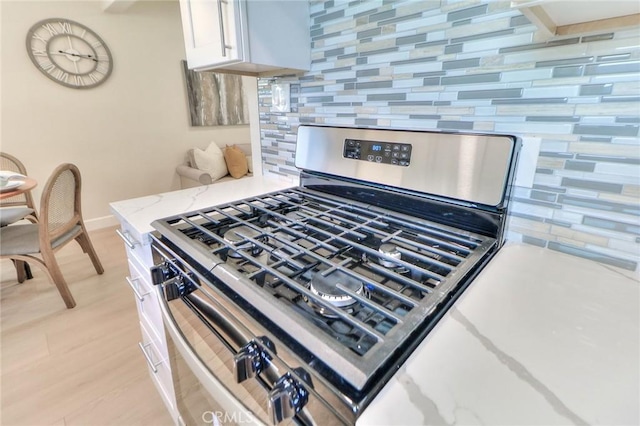 16928 Pocono St, La Puente, CA 91744 - kitchen view of gas stove, backsplash, light wood finished floors, baseboards, and white cabinets