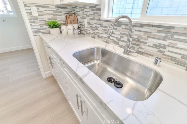 16928 Pocono St, La Puente, CA 91744 - kitchen view of a sink, white cabinets, tasteful backsplash, and light wood-type flooring