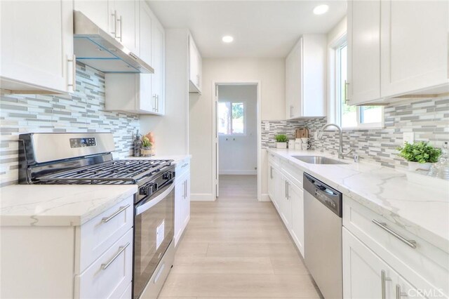 16928 Pocono St, La Puente, CA 91744 - kitchen featuring stainless steel appliances, under cabinet range hood, a sink, baseboards, and light stone counters