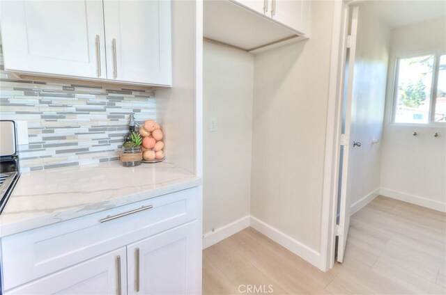 16928 Pocono St, La Puente, CA 91744 - kitchen featuring baseboards, light wood finished floors, light stone countertops, tasteful backsplash, and white cabinets