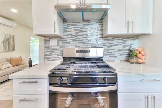 16928 Pocono St, La Puente, CA 91744 - kitchen featuring stainless steel gas range, under cabinet range hood, a wall mounted AC, white cabinets, and decorative backsplash
