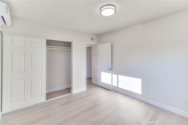 16928 Pocono St, La Puente, CA 91744 - unfurnished bedroom with a wall mounted air conditioner, baseboards, light wood-style flooring, and a closet