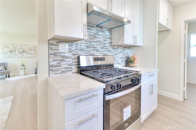 16928 Pocono St, La Puente, CA 91744 - kitchen featuring stainless steel gas stove, under cabinet range hood, light wood finished floors, decorative backsplash, and light stone countertops
