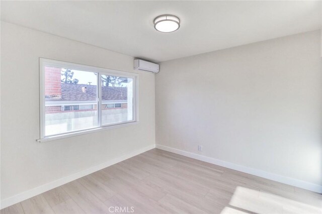16928 Pocono St, La Puente, CA 91744 - unfurnished room with a wall unit AC, light wood-type flooring, and baseboards