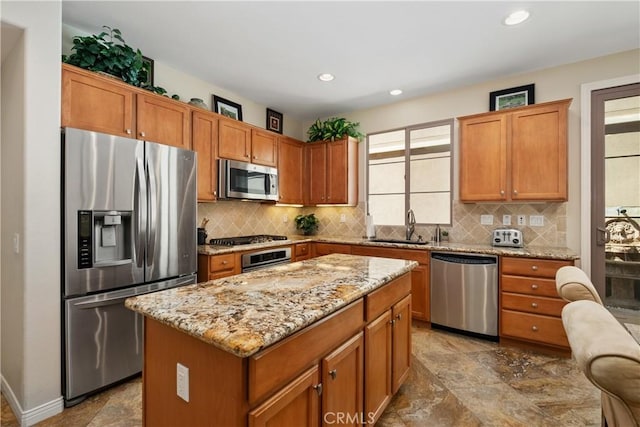 kitchen featuring stainless steel appliances, a sink, tasteful backsplash, light stone countertops, and a kitchen island