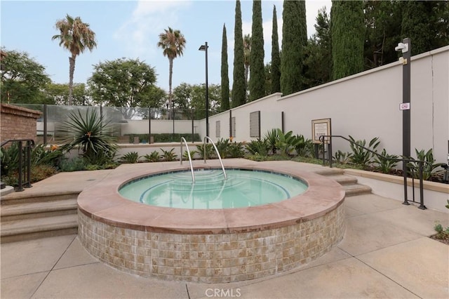 view of pool with a community hot tub and fence