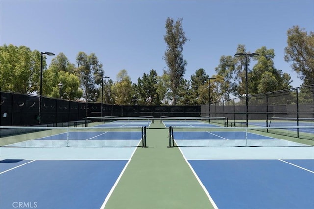 view of tennis court with community basketball court and fence
