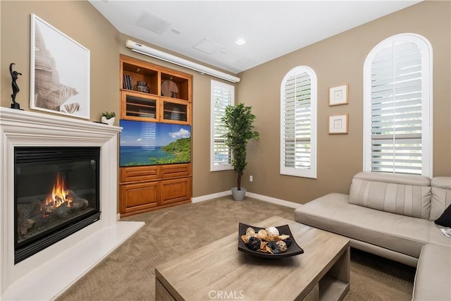 carpeted living area featuring a glass covered fireplace and baseboards