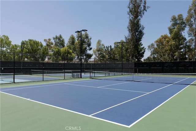 view of tennis court with community basketball court and fence