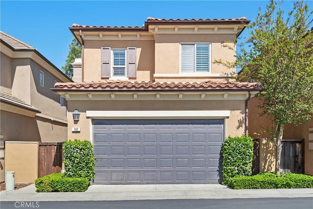 mediterranean / spanish-style home with an attached garage, driveway, stucco siding, and a tiled roof